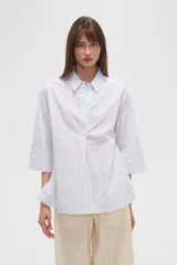 Camisa celeste a rayas verticales, de corte holgado y manga 3/4.