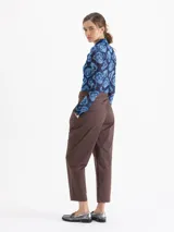 Pantalón negro de tiro alto, estilo mom fit, confeccionado en poplin con spandex. Presenta tablas en la cintura con cinto de hebilla de cadena dorada, canesú y pinzas delanteras.