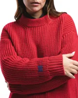 Sweater unisex de lana merino fina color rojo, con cuello redondo y corte relajado. Presenta un motivo inspirado en la técnica de zurcido visible.