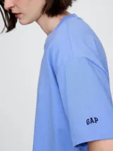 Remera corta color blanco con logo de Gap estampado en el frente y mangas cortas con detalle de rayas horizontales.
