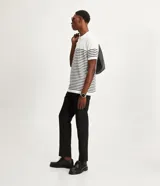 Polo de hombre con corte comfort, confeccionada en tejido de punto de algodón a rayas horizontales blancas y negras. Tiene cuello inglés con botones y mangas cortas.