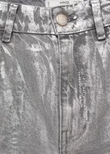 Pantalón de jean plateado de tiro alto, corte recto, con cierre de cremallera y botón, cinco bolsillos y trabillas.