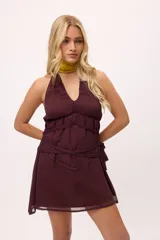 Minivestido negro con escote halter, espalda descubierta, cintura drapeada y falda con transparencias.