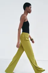 Pantalón de vestir color verde oliva, de tiro medio, corte flare y bolsillos laterales.