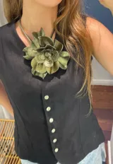 Colgante con dije grande en forma de flor de cuero color verde metalizado, con cordón rígido plateado.