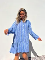Vestido camisero corto celeste con bordado de flores blancas, corte recto y mangas largas.