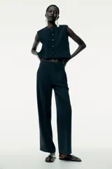 Top tipo chaleco negro de Zara Woman Collection, con cuello redondo y sisa. Presenta costuras a contraste y cierre frontal con botones.