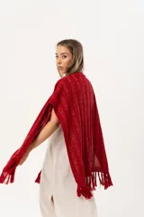 Ruana tejida de hilo color rojo con lurex y terminación de flecos.