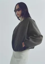 Chaqueta bomber verde oliva de lana con cierre frontal con cremallera, cuello redondo, puños y bajo elásticos.
