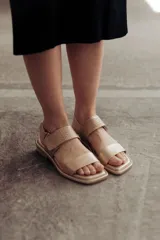 Sandalias bajas doradas de cuero, con punta cuadrada, tiras anchas y cierre con hebilla ajustable.