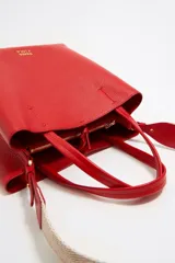 Bolso tote negro de cuero vacuno con doble asa corta y correa de tela extraíble. Interior con tres compartimentos y bolsillo con cremallera. Logo metálico de la marca en el frente.
