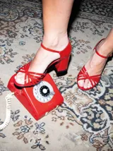 Sandalias negras de charol con tiras cruzadas en el empeine, pulsera con hebilla al tobillo y tacón cuadrado.