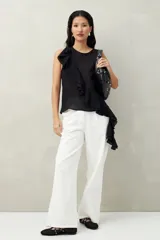 Top blanco de tencel sin mangas, de corte asimétrico, con volados en diagonal.