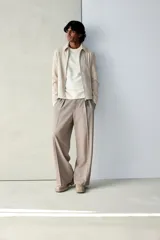 Campera color beige de tejido suave con cuello, cierre frontal, puños ajustables con botón a presión y bolsillos insertados al bies. Corte estándar y mangas forradas.