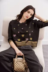 Camisa negra de viscosa con jacquard de lurex, calce amplio y escote redondo. Presenta bordados de corazones dorados y rosados, y guardas doradas en el ruedo y los puños.