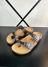 Sandalias de dedo marrones con tiras de ecocuero y hebillas metálicas.