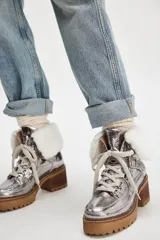 Botas de caña baja plateadas con cordones, suela track color marrón, taco cuadrado y cuello de piel sintética blanca.