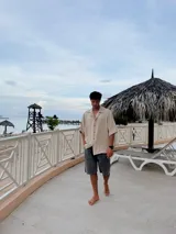 Camisa beige de corte amplio, con cuello clásico, manga corta y cierre frontal con botones.