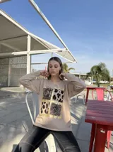 Remera roja de manga larga con cuello en V y estampado frontal con recuadros de animal print en dorado.