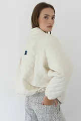 Campera acolchada color crudo con patrón de rombos, cuello alto y cierre frontal.