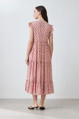 Maxi vestido de corte imperio, color rosa con estampado floral liberty en tonos fucsia. Tiene escote en V, mangas cortas con volados y falda larga con volantes. Cierre frontal con botones.