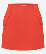 Short pollera de color rojo confeccionado en tejido de viscolino, una mezcla de lino y viscosa. Presenta un diseño de cintura fija con cierre de cremallera lateral y bolsillos frontales con solapa.