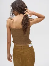 Top corto negro con textura fruncida, tirantes finos con lazos ajustables y corte crop.