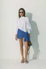 Blusa blanca de lino con cuello fruncido y botones frontales.