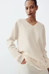 Jeans de tiro alto con diseño wide leg y largo completo. Presentan una estructura de cinco bolsillos, cintura con trabillas y cierre frontal con cremallera y botón. El diseño destaca por su patrón de rayas verticales a contraste sobre fondo claro.