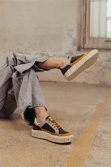 Zapatillas deportivas de cuero color beige con detalles en lila y amarillo.