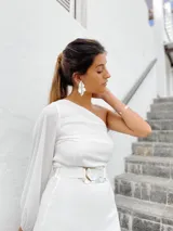 Vestido corto blanco con un hombro descubierto y una manga larga abullonada. Incluye cinturón con hebilla de alpaca y nácar.