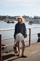 Campera de jean negra tipo bomber con cuello redondo y cierre frontal con botones metálicos. Presenta un parche rectangular con diseño gráfico en la espalda.