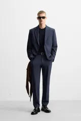 Blazer azul marino con sutil diseño de cuadros, corte regular fit, cuello con solapas de muesca, manga larga con puños abotonados, bolsillo de vivo en el pecho, bolsillos de solapa en la cadera, bolsillo interior, aberturas en la espalda y cierre frontal con dos botones.