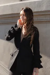 Blazer negro de lino con silueta estructurada, cierre de un botón y volantes en capas en mangas y bolsillos.