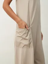 Mono largo color beige, de corte holgado, con cuello redondo y mangas cortas. Presenta bolsillos laterales y detalle de costuras verticales en el frente.