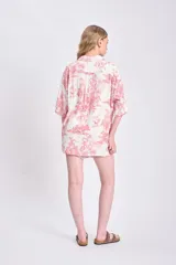 Camisa de manga corta oversize de lino con estampado de palmeras y animales en color rojo sobre fondo blanco.