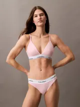 Conjunto Calvin Klein Modern Cotton color rosa pálido, compuesto por un corpiño triángulo con copas sin relleno y una bombacha tipo bikini. Ambos con banda elástica blanca con logo de la marca.