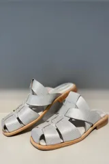 Zueco plateado con tiras de cuero entretejidas y suela de madera.