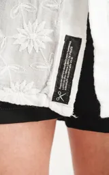 Camisa blanca con bordado de flores blancas, de manga corta y corte recto.