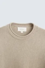 Sweater color arena de punto con cuello redondo y manga larga. Tejido con mezcla de algodón y cashmere.