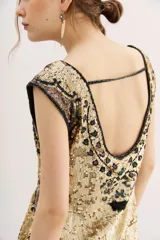Vestido corto dorado con lentejuelas y estampado abstracto en tonos marrones y negros.