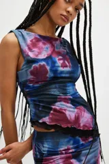 Top sin mangas de mesh con estampado floral en tonos azul y rosa, con detalle de frunce lateral y ribete de encaje negro en el ruedo.