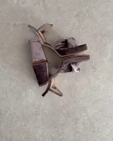 Sandalia de cuero vacuno color dorado, con plataforma y taco cuadrado. Presenta una tira delgada en el tobillo y detalle de nudo en la capellada.