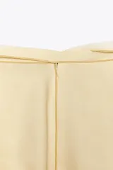 Falda midi color crema con estampado floral difuminado en tonos marrones y verdes. Tiene cintura ajustable con lazos y abertura en la parte trasera. Cierre con cremallera oculta en la costura.