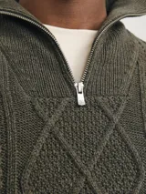 Sweater de punto trenzado color marrón con cuello alto y cierre de cremallera.