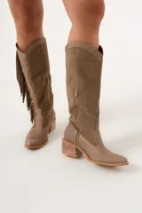 Bota texana de caña alta color visón, 100% cuero hecha a mano en Uruguay, con cierre lateral y taco de 5,5 cm. Tiene flecos en los costados internos.