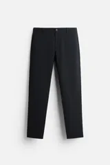 Pantalón negro de corte slim fit, confeccionado en tejido elástico. Cuenta con cintura elástica, bolsillos frontales y traseros de vivo. Cierre frontal con cremallera y botón.