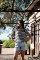 Remera de punto gris con rayas horizontales celestes, corte recto y mangas cortas.