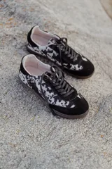 Zapatilla urbana con capellada de cuero con textura tipo pelo con estampado animal print en marrón y blanco, detalles en gamuza marrón, cordones marrones y suela de goma color caramelo.