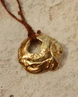 Collar con cordón naranja y dije de flor dorada.